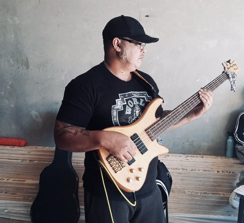 Man wearing baseball cap holding bass guitar