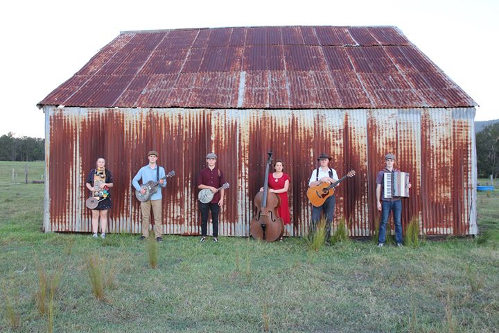 Haystack Mountain Hermits musicians standing in front of shed